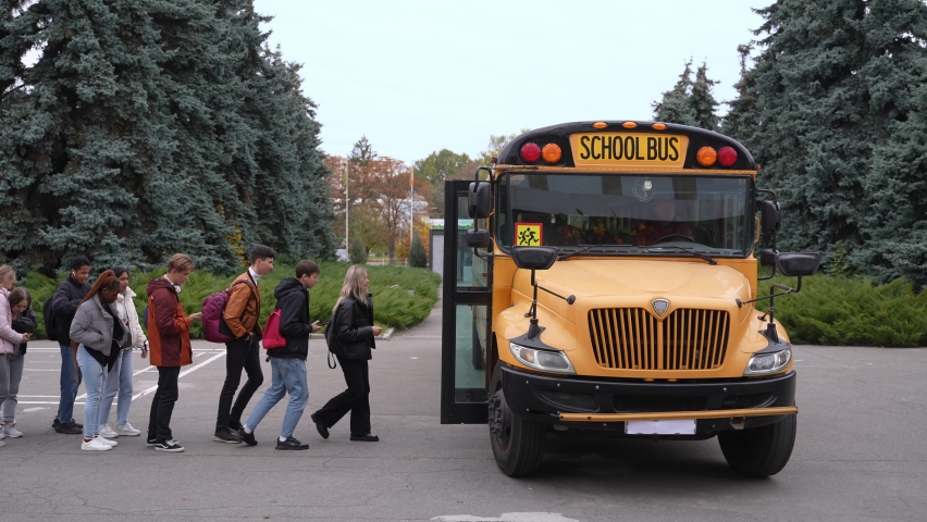 Side view of multinational high school students with backpacks getting on yellow school bus after lessons. Queue of diverse secondary school pupils boarding school bus to go home after classes Royalty-Free Stock Footage #1086417428