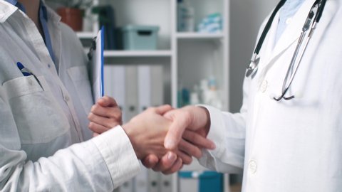 Doctors shake hands with each other. The meeting of doctors embraced hands. Greetings from two doctors. Meeting of doctor and nurse. Shake each other's hands. An office in a hospital shaking hands
