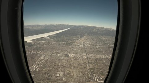 Aerial view from airplane window porthole during landing in Los Angeles, LAX. Beautiful view from airplane window. Ultra wide-angle POV shot from a window seat of an airplane. 