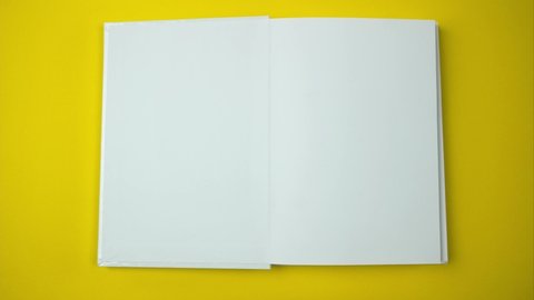 White book appears quickly rotating on a yellow background. Top view blank sheets of open book. Stop motion