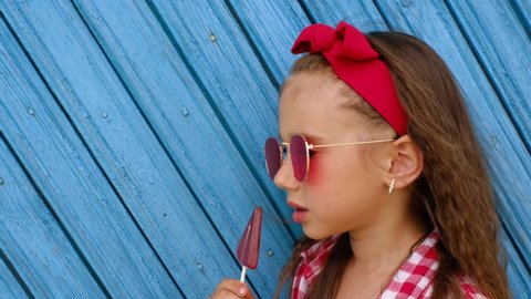 The girl eats a sweet lollipop, licking and enjoying the candy. Harm from the use of sugars. Risk Of Developing diabetes