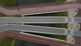 Beautiful dynamic bridge built in the city center of Leiden, Netherlands. The bridge is used by cyclists and car drivers. 4K video clip shot from a top-down perspective.