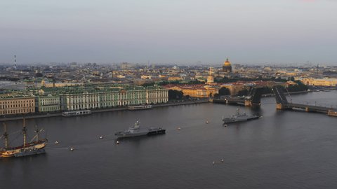 Aerial landscape of a replica of the ancient frigate Poltava and modern cruisers before the holiday of the Russian Navy at early morning, water area of Neva river, Isaac cathedral, Winter palace