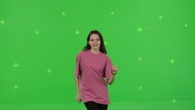 Close-up of young woman dancing on a green screen background. Girl makes a gesture with her hands as if swipping the page to the side . Chroma key