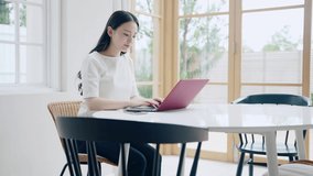 Young asian woman using a laptop PC in the room. Orbit shot.