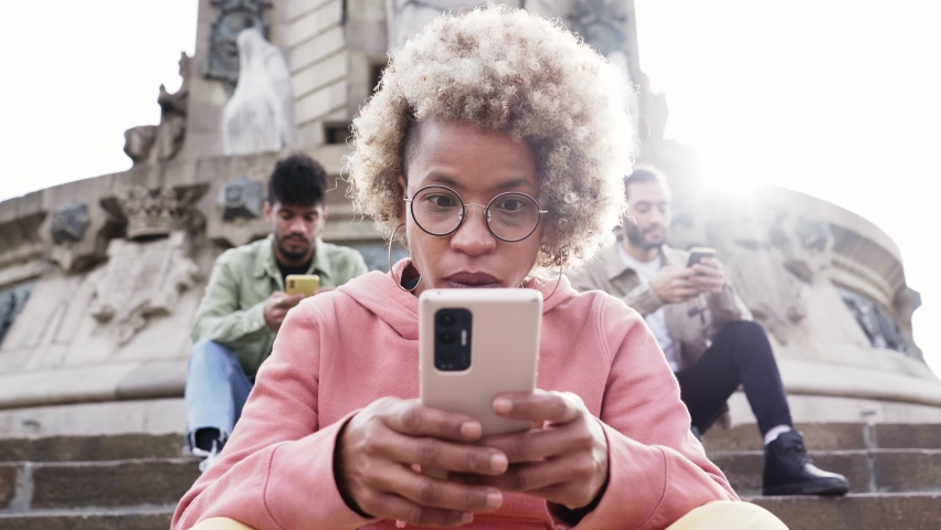 Group of people using phone with serious face and ignoring each other. A woman focused on their mobile sitting on a staircase in a city. Technology addicts concept. Royalty-Free Stock Footage #1086430244
