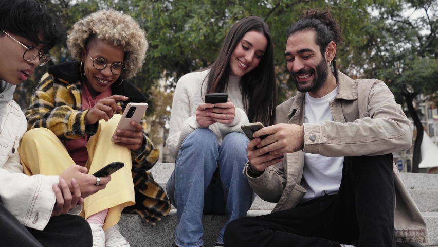 Group of four friends watching something funny at mobile cell. Happy people using phone and having fun Royalty-Free Stock Footage #1086430598
