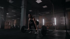 Slow motion: A woman lifts a barbell in a dark gym with a lot of weight. A strong young woman lifts weights for a workout - Powered by Shutterstock - Get 15% off with code: PIKWIZARD15