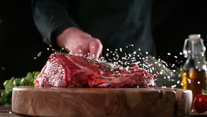 Close-up of falling tasty beef steak in kitchen, super slow motion, camera movement, filmed on high speed cinematic camera at 1000 fps.