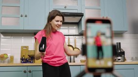 Young girl dancing, sing using hair dryer and filming videos for blog or social network. Blogger recording vlog with trend content in kitchen for media account. Slow motion ready, 4K at 59.97fps.