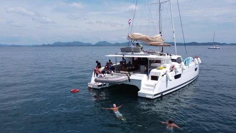 Phuket, Thailand, 20, December, 2019:
A group of elderly tourists swim in the sea, tourists rest while walking on a sailing catamaran