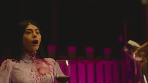 Angry Man suddenly spilling glass of red wine on young girl's shirt . Feminism , abuser , domestic violence , disrespectful man concept . Purple background slow motion .  Boy or waiter pouring wine 