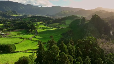 Aerial shot of green meadows, mountains and Furnas city on Sao Miguel Island, Azores, Portugal. Azores nature on sunny day