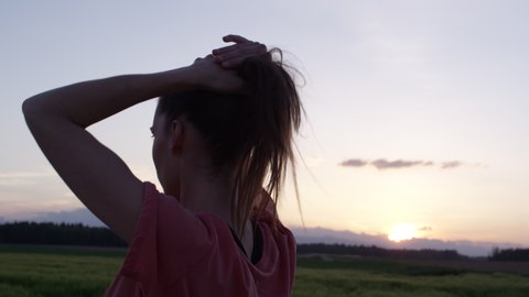 Young Woman Putting Her Hair In Ponytail Before Sports Training At Sunset In Slow Motion