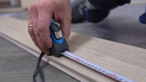Tape measure rolling tool in hands of professional worker man. Tape line instrument using, building and repair equipment. Construction, projecting, planning indoors, male job. DIY building close up.