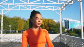 A girl with dark skin is engaged in fitness by him in an orange tracksuit against the background of the sea 4k video