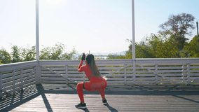 A girl with dark skin is engaged in fitness by him in an orange tracksuit against the background of the sea 4k video art
