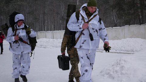Kharkiv, Ukraine - January, 31, 2022: Ukrainian soldiers in camouflage are walking with backpacks on a snowy road. Soldiers prepare to defend Ukraine from Russian attack