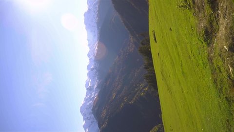 slender, beautiful blonde woman rides on large swing against background of mountains in Georgia, Svaneti heshkili. view from back. She admires view of mountains and altitude of flight. vertical video