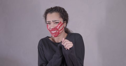 Afro-latina woman, serious, with red handprint on her face, saying no, being assaulted, afraid, begging not to be beaten, symbol of impotence, video prevention of violence against