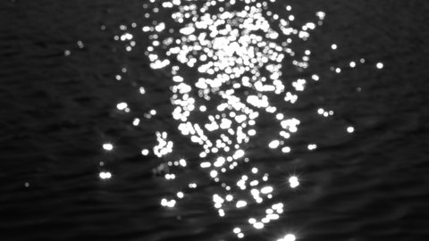 Black water texture with white sun or moon light bokeh reflection. Dark surface organic 4k video background. Rippling and sparkling river or lake