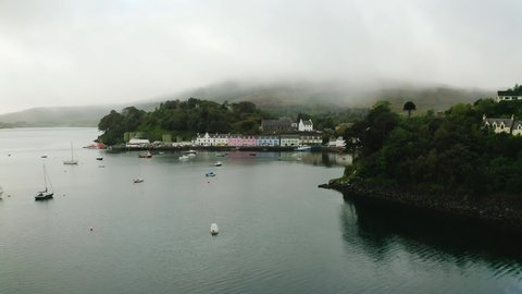 Beautiful green, blue, red and yellow colored houses at Loch Portree on the isle of Skye in Scotland on a foggy day. Low angle drone panning shot