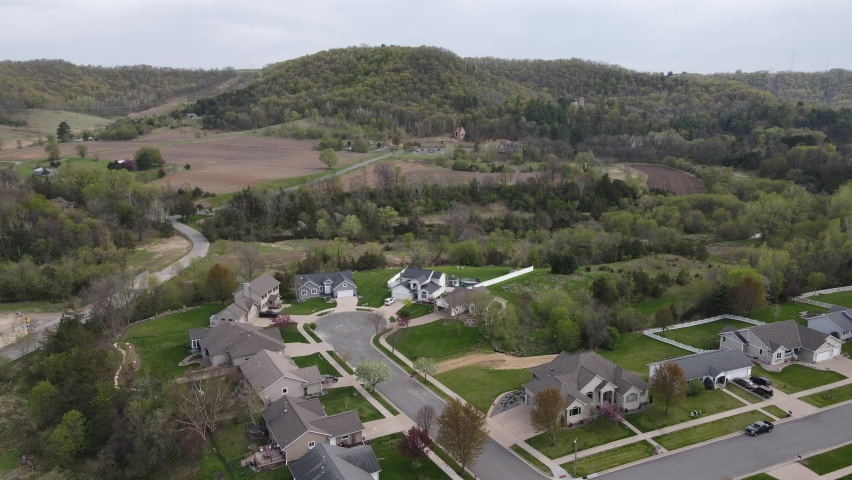 Residential neighborhood nestled in a valley in midwest Wisconsin. Mountains and woodlands rising up to the sky in autumn. Farm fields plowed. 
