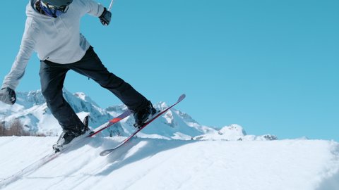 SLOW MOTION TIME WARP: Cinematic action shot of a male skier jumping off a large kicker. And doing a trick. Freestyle skier does a breathtaking spinning trick while exploring the fun park slopes.