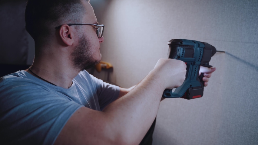 A man drills a wall with a hammer drill in his apartment Royalty-Free Stock Footage #1086476174