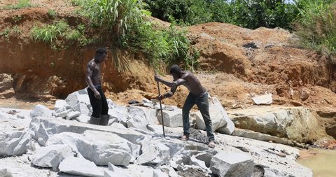 BO, SIERRA LEONE - 10 OCT 2021: Breaking rock men in Rock quarry Kenema Sierra Leone hard labor. Sierra Leone, Africa Quarry where rock and stone is mined for commercial use in roads, cement.