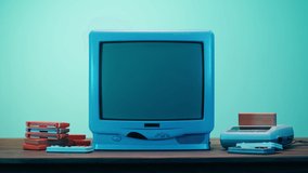 Old television with grey interference screen on blue neon background. Close-up of vintage tv and cartridges for retro playstation. Antique video game, nostalgia. 