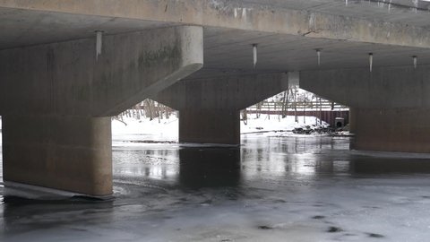 Frozen river under bridge with dripping icicles