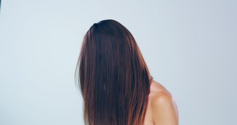Beautiful, bold and brunette. 4k video footage of a beautiful young woman flicking her hair in the studio.
