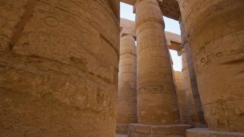 Majestic columns with ancient Egyptian drawings, sun comes out from behind the column. Karnak Temple in Luxor, Egypt Royalty-Free Stock Footage #1086490337