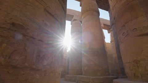 Majestic columns with ancient Egyptian drawings, sun comes out from behind the column. Karnak Temple in Luxor, Egypt