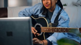 Young Asian Woman Learning Acoustic Guitar Online, By Laptop
