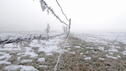 Winter wasteland with barbed wire fence on an empty field, scary fog in the back