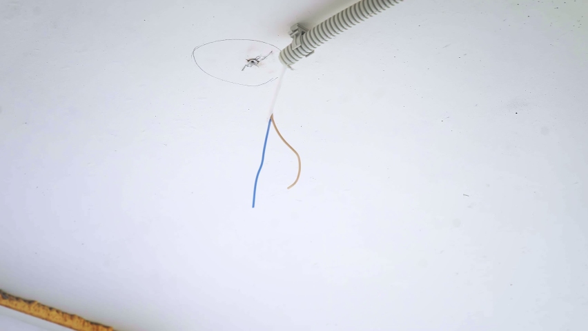 A male electrician connecting a ceiling lamp to electrical wires in a new apartment building. Close-up Royalty-Free Stock Footage #1086492305