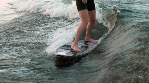 A female surfer jumping on a wakeboard. An experienced wakeboarder splashes water drops into the camera.