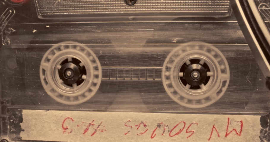 Stack of cassettes and one spinning in player. Old cassette and player.