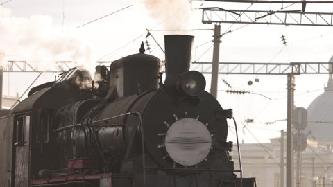 Vintage steam train locomotive, locomotive wheels. High quality. Steam train departs from railway station. Old vintage steam train on the rail road. Smoke covering