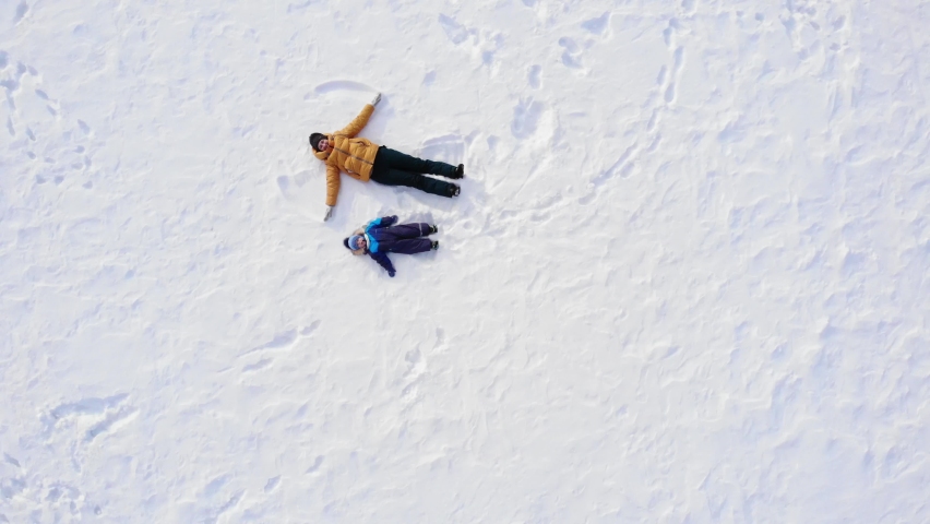 mom and baby make a snow angel. aerial photography