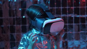 fashionable boy child in a silver shirt and blue hat and glasses virtual reality playing a game. the color of cyberpunk is blue and red