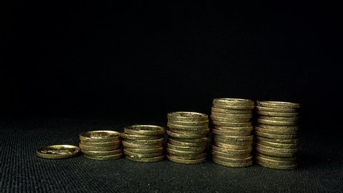 Video of gold coins piled up one after another in front of black background. Fixed shooting. Savings, investment, business, success image