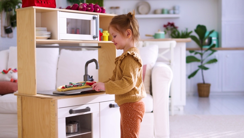 cute little baby girl plays on a toy kitchen, pretending to make pizza in the oven Royalty-Free Stock Footage #1086502442