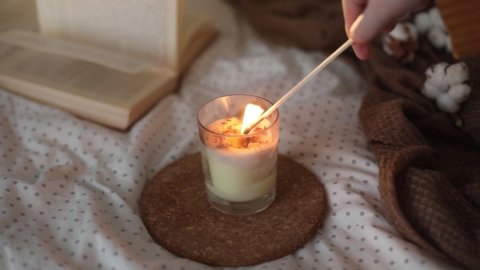 Cozy still life interior details with a book, burning candle and a cotton twig in warm soft bed. Sweet home. Full HD video