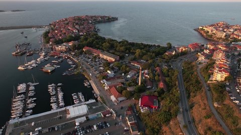 Drone view of a Sozopol port and old town during summer sunset. Bunch of boat floating into the sea waters. Seaside town with developed traffic. Sunset in the season of summer