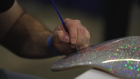 Los Angeles, CA USA - Jan 20 2022: This video shows an artist's hand painting custom pinstripes artwork on a silver metal flake fender.