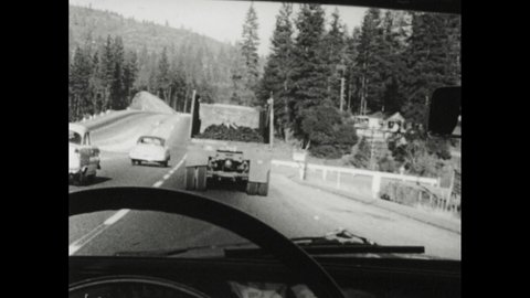 1950s: Windshield view of car behind heavy truck going uphill. Car passes truck on left. Sign "End Freeway 14 mile".