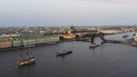 Aerial landscape of a replica of the ancient frigate Poltava and modern cruisers before the holiday of the Russian Navy at early morning, raised Palace bridge, Isaac cathedral, Winter palace, Rostral